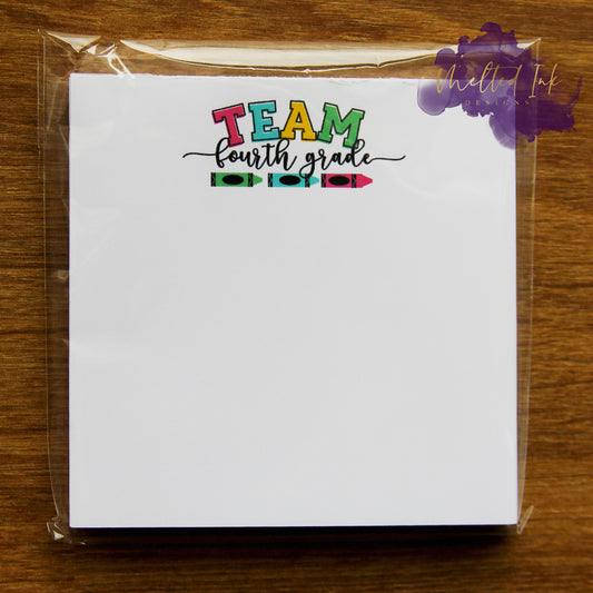 Photo is of a 3.5x3.5 notepad and at the top says Team Forth Grade with a green, blue and pink crayon. 