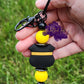Photo consists of a beadable keychain bar that has a thin yellow line badge with solid yellow accenting silicone beads. 