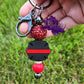 Photo consists of a dark gray beadable keychain bar that has a thin red line firefighter badge. It is accented with an acrylic spacer, a solid red silicone bead and rhinestone spacer.