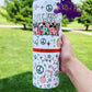 The photo features a festive 20oz Christmas tumbler adorned with the cheerful phrase "Tis the season to be merry." The design incorporates vibrant red, light pink, and light green colors, creating a joyful holiday spirit. It includes playful elements like candy canes, a peace sign, Santa hats, and colorful Christmas lights. Scattered throughout are stars and polka dots in light green and red, adding to the overall whimsy. 