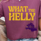 Large bold yellow retro lettering that reads “What The Helly.” The font has a playful, vintage ‘70s look with thick, curved letters.