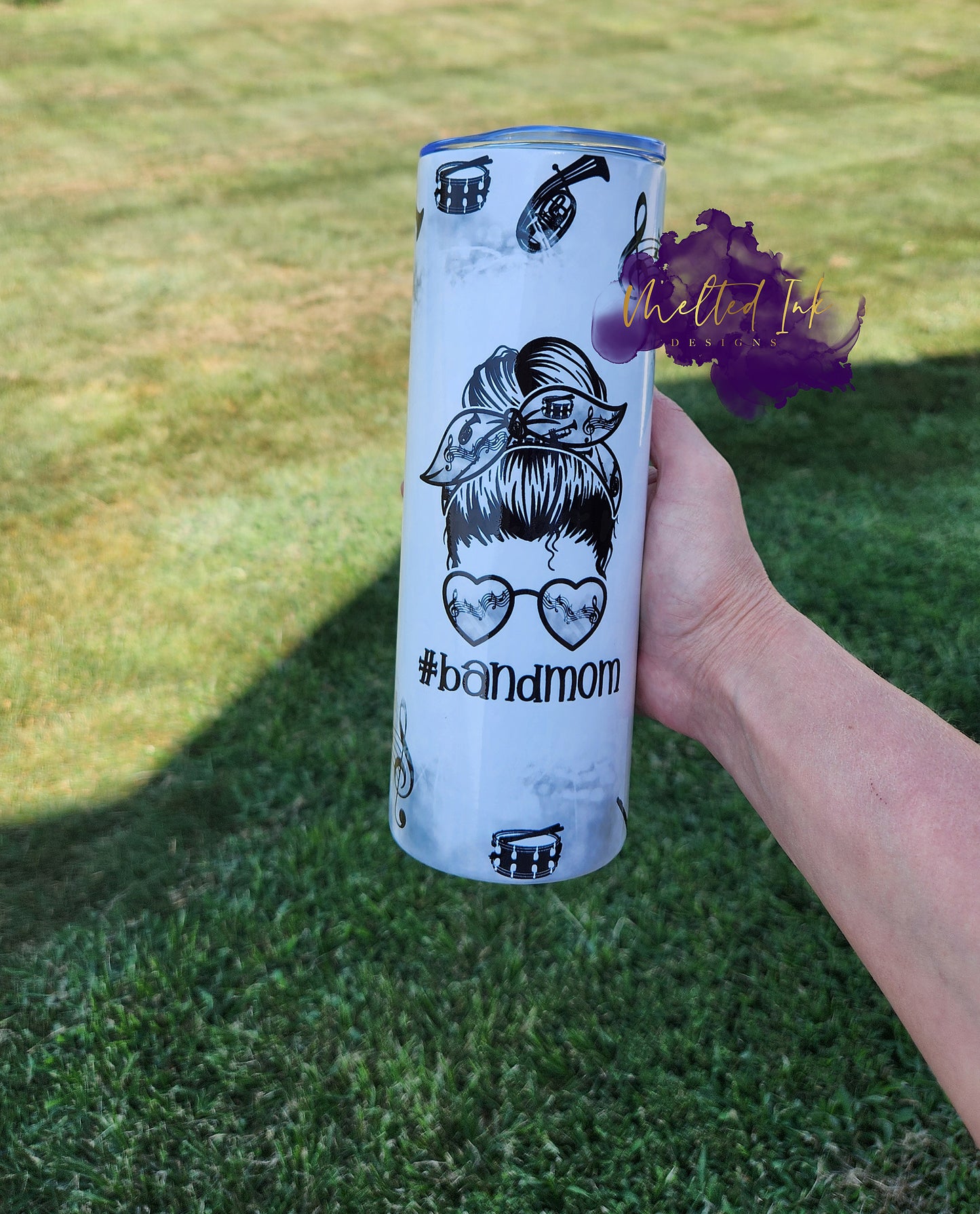 Photo is a 20oz tumbler that says #bandmom. Has a picture of a girl head with her hair up with a headband and sunglasses that has music elements on them as well as the cup that consists of drums, music notes, etc.