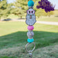 his lanyard features an adorable focal bead of a ghost reading a book, capturing a whimsical and playful vibe. It is accented with light blue and pink silicone beads, along with sparkling rhinestones, adding a fun touch to the design. The lanyard also includes a keyring .