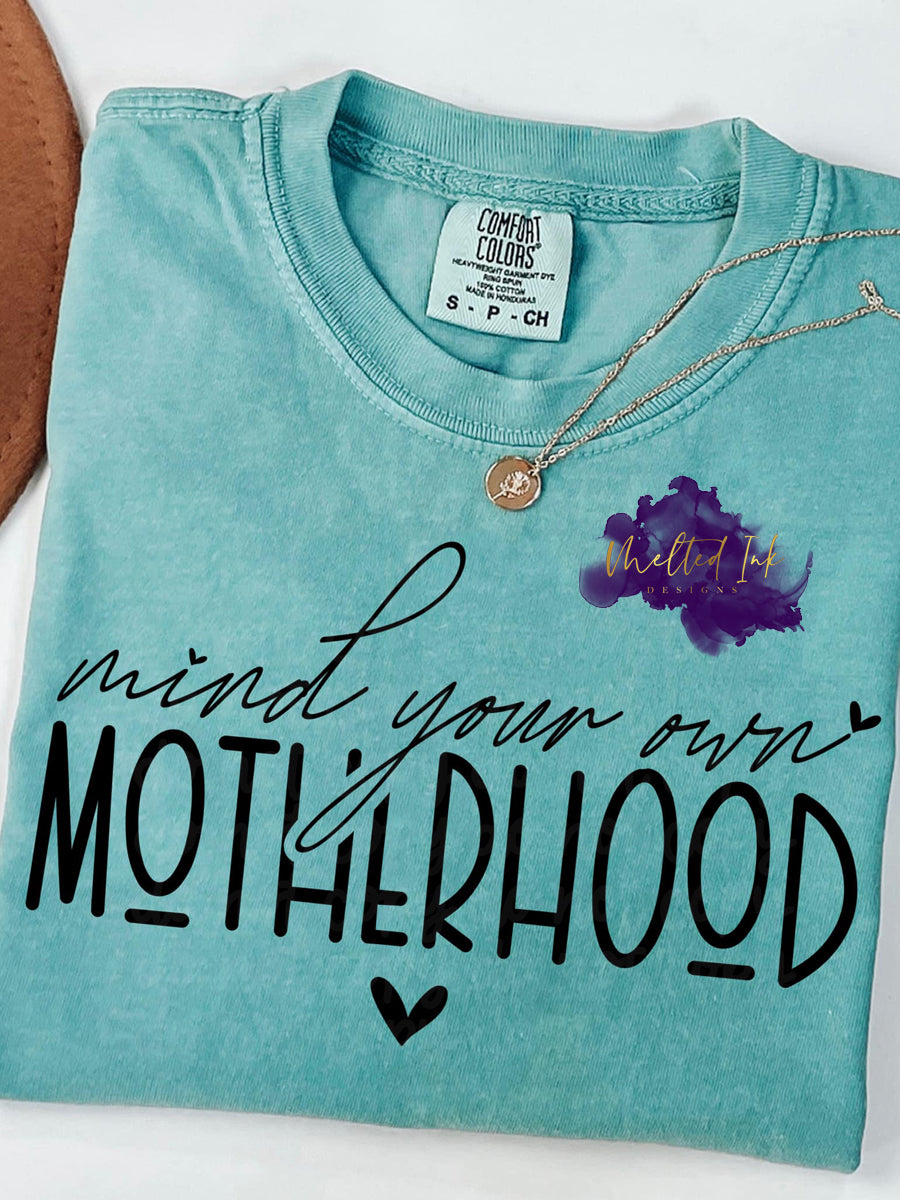 Photo is a mock up of the design and the design says mind your own motherhood. 